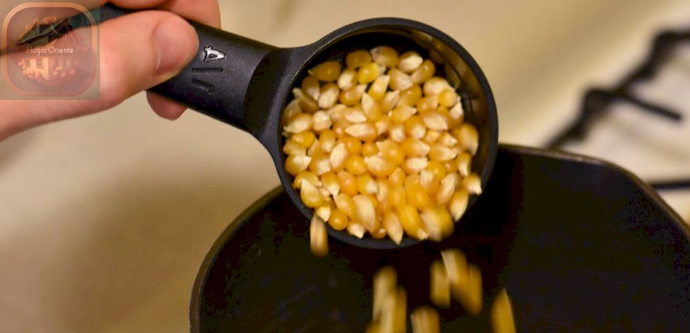 taza medidora llena de granos de palomitas de maíz vertidos en una olla
