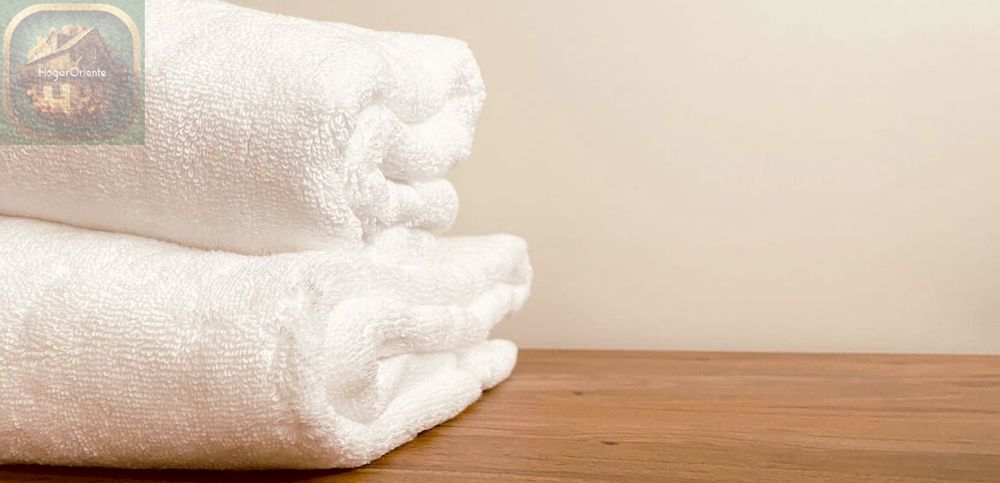 dos toallas blancas apiladas sobre una mesa de madera