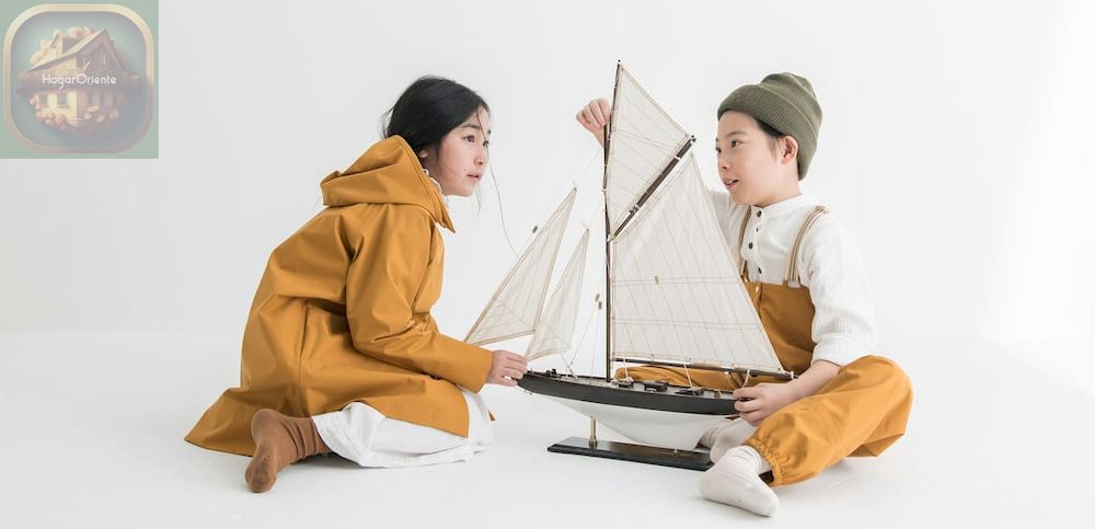dos niños con ropa impermeable jugando con un modelo de barco