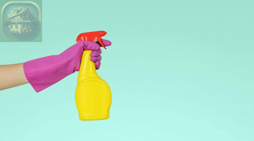 mano enguantada sosteniendo una botella de spray de limpieza