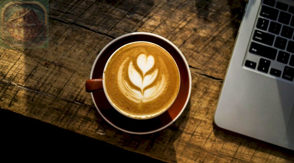 café con leche en la mesa de madera junto a la computadora portátil